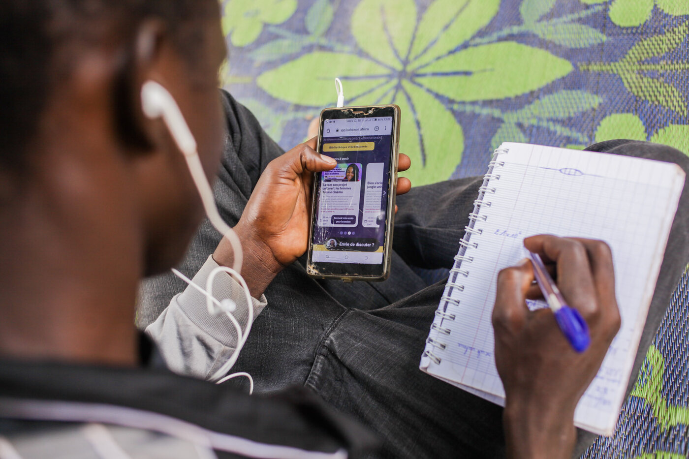 A learner with the Kabakoo app on a phone and a notebook.